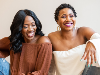 two black women sitting down and smiling