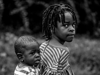 a girl carries a younger child on her back
