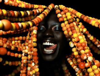 woman with colorful beaded dreadlocks against a black background
