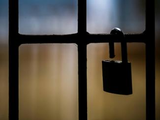 brass padlock on black metal fence 