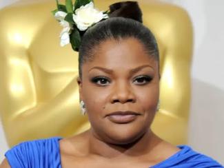 Mo'Nique standing in front of oscars statue