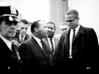 malcolm x and mlk standing together with police presence 