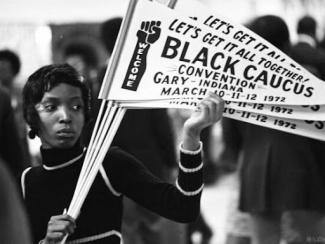 black woman holding up banner at the national black political convention