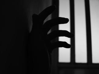 hand reaching out of a jail cell
