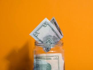 glass jar filled with money sitting on top of a table