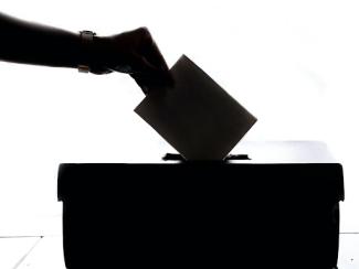 person placing a ballot in a box