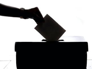 person dropping paper in a ballot box