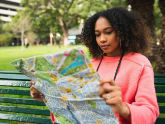 black woman sitting down on a bench holding a map