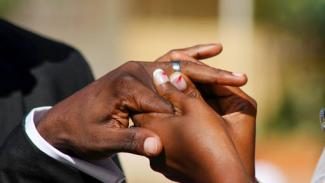 black woman fitting ring to black man's hand