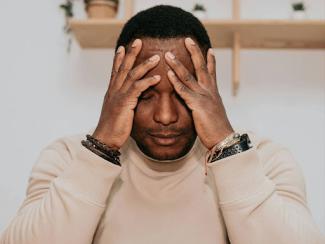 black man covering his eyes with his hands