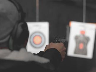 person holding a gun at a shooting range doing target practice 