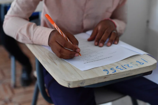 black person leaning forward on a desk with a test on the desk