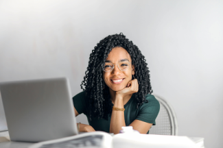 happy woman sitting at a table with a laptop