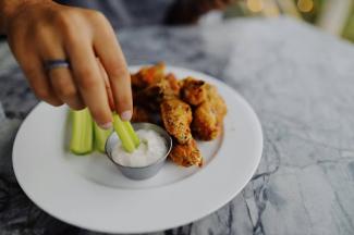 person dipping celery in ranch dip