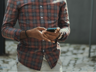 man in red blue and white plaid dress shirt wearing yellow hat holding black smartphone