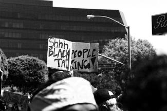 grayscale photo of man in white cap and black sunglasses holding sign