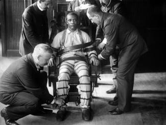 black man being strapped in an electric chair
