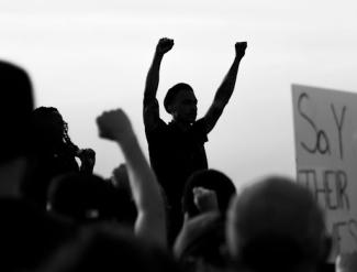 grayscale photo of people raising their hands