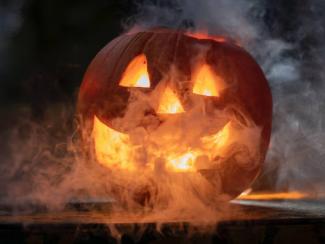 carved pumpkin with light inside and smoke coming out