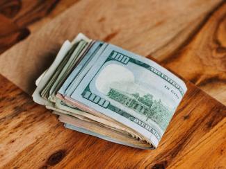 wad of cash on a wooden table
