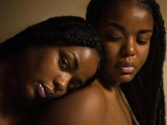 one black woman leaning on another black woman's shoulder