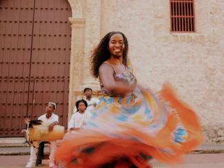 a woman in a colorful dress dancing in front of a group of people