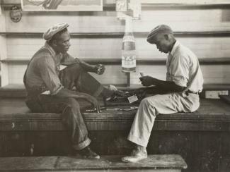 grayscale photo of two mean sitting on bench