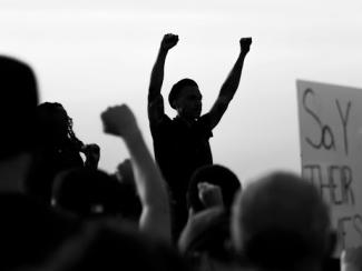 grayscale photo of people raising their hands