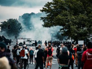 crowd of protestors with tear gas in the air 
