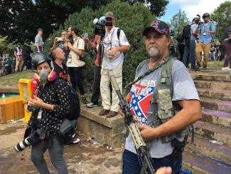 white supremacist standing with a large gun at a rally