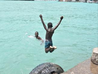 younger black boy jumping into pool