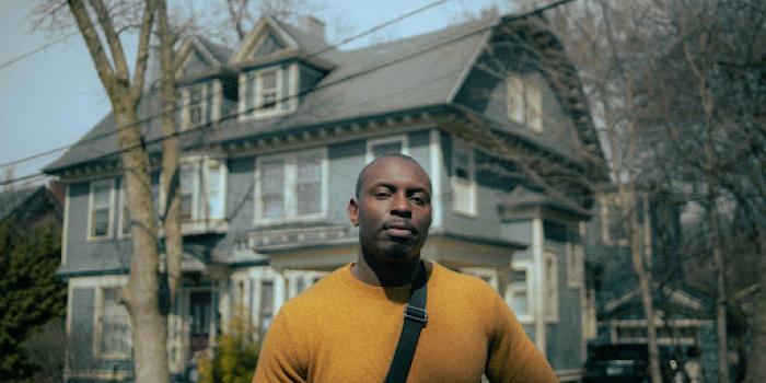 man in yellow crew neck long sleeve shirt standing near building in the daytime