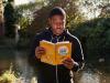 black man in black and white hoodie holding yellow book