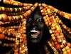 woman with colorful beaded dreadlocks against a black background 