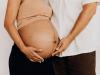 a man and a pregnant person holding their pregnant belly